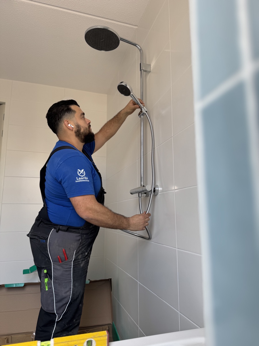 Soufiane Douhou monteert een regendouche in een nieuwe badkamer